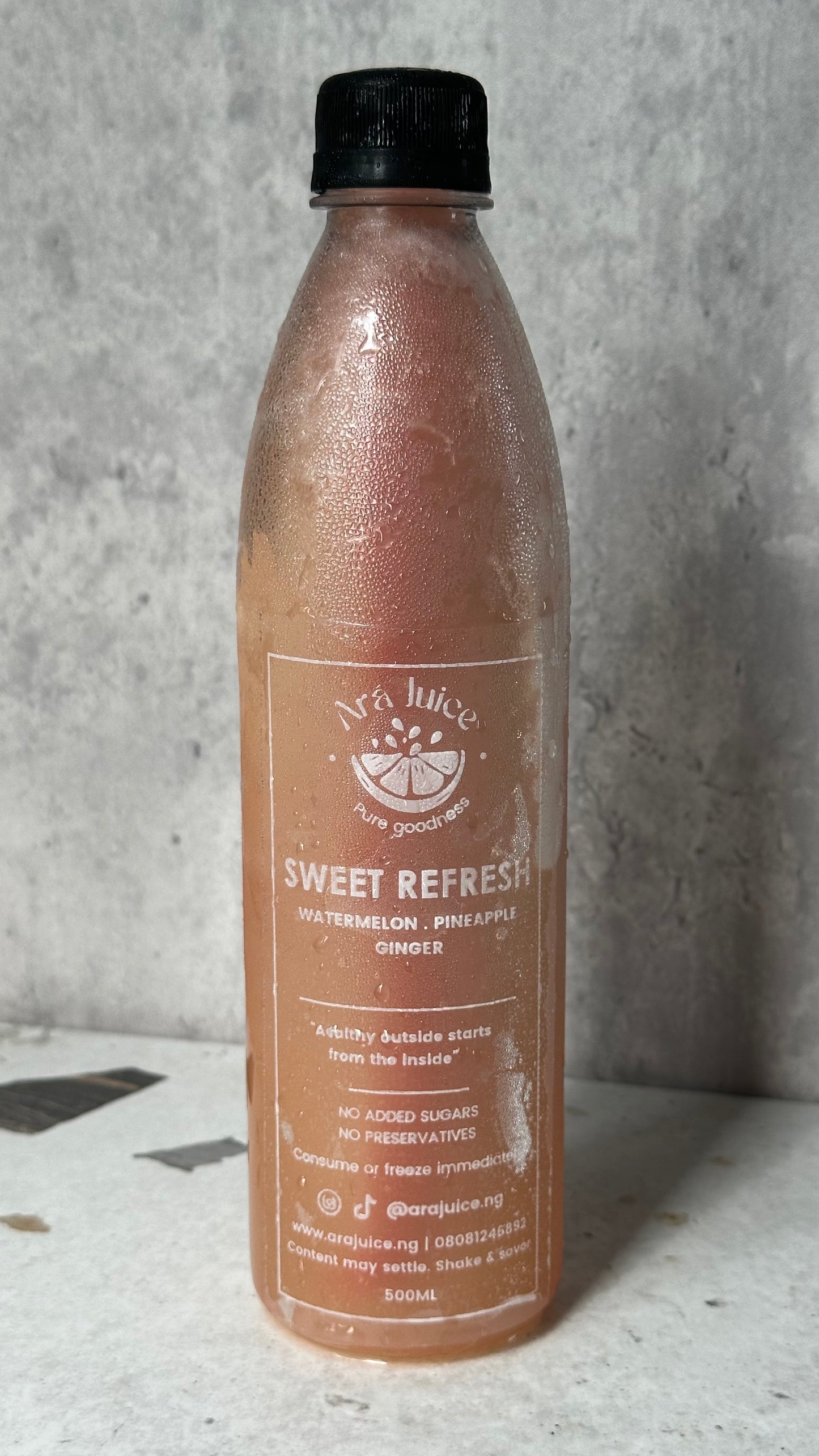 Bottle of 'Sweet Refresh' juice with a black cap on a gray background