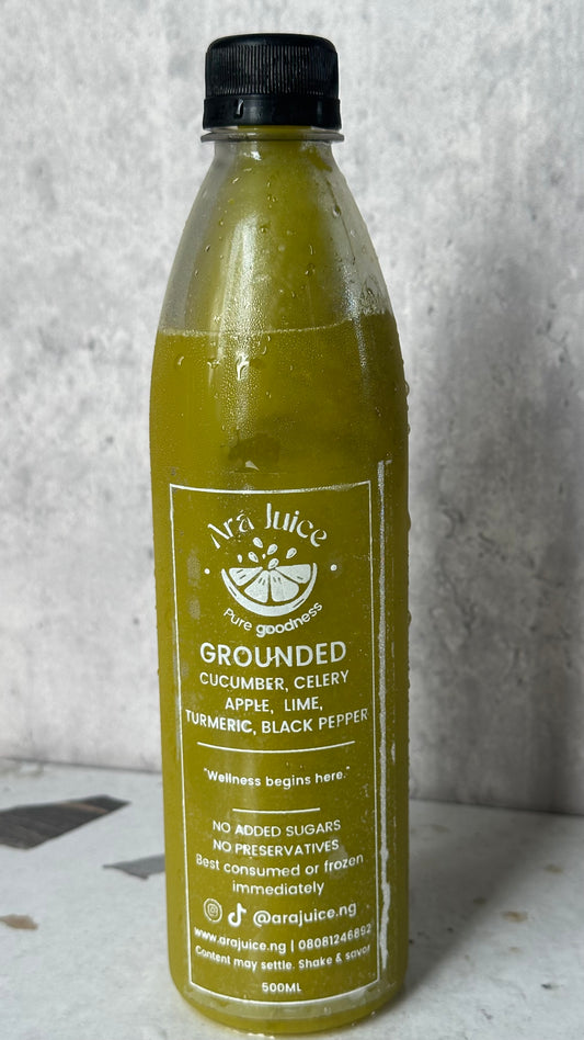 Bottle of Ará Juice 'Grounded' green juice with a black cap on a gray background